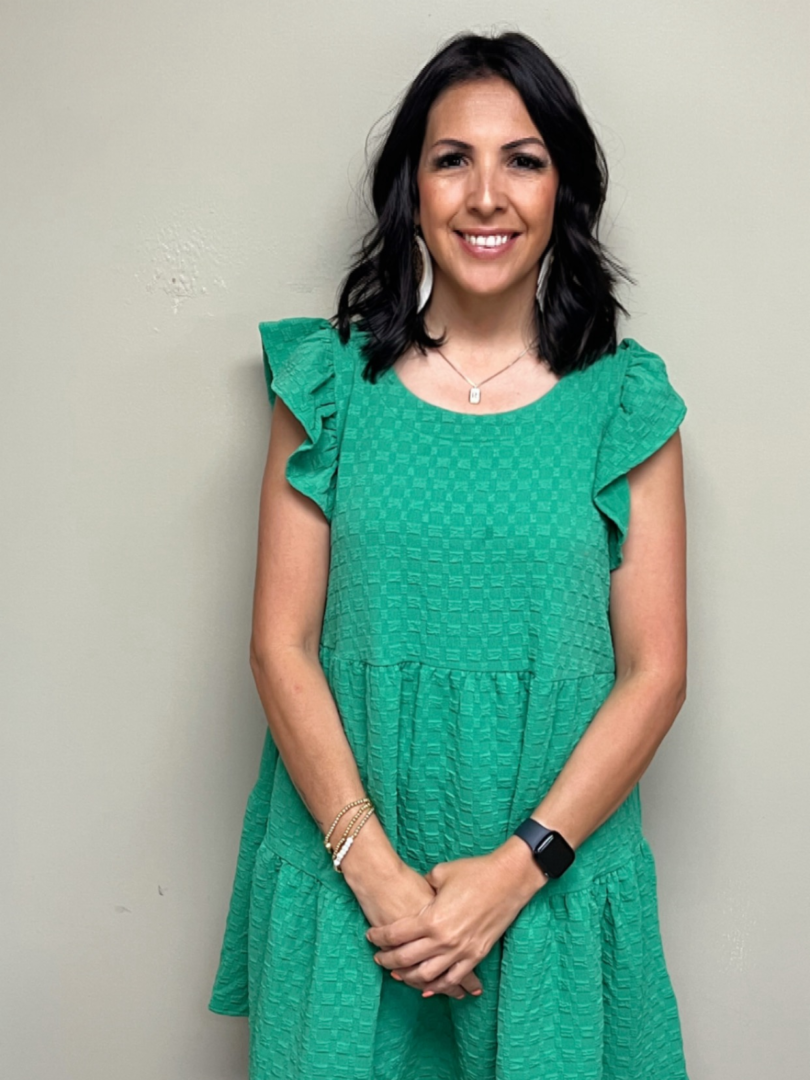 A woman in green dress smiling for the camera.